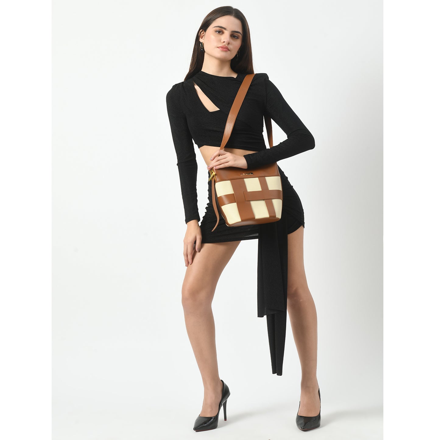 A woman in a black long-sleeve crop top and asymmetrical skirt carries a stylish beige and brown canvas bucket bag, exemplifying the blend of fashion and function in ladies' canvas handbags.